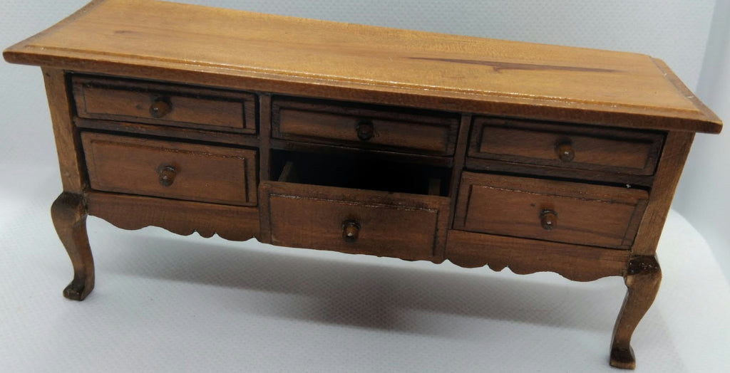 A vintage wooden sideboard with 6 drawers and carved legs, and a warm medium-brown finish, photographed against a plain white background.