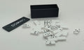 Dolls house miniature White dominoes with black pips scattered on a white surface next to a black domino box and a black tag labeled DOMINO. 