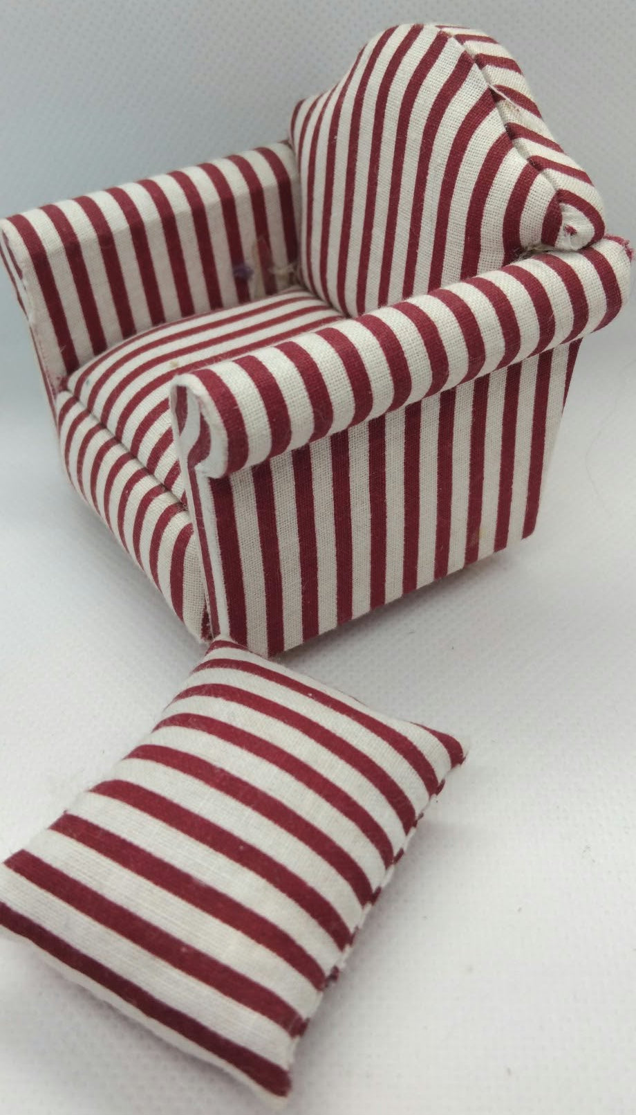 A miniature armchair and matching throw pillow set, both upholstered in a red and white striped fabric, shown on a plain light gray background.