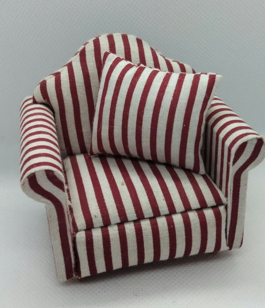 A miniature armchair with red and white vertical stripes, featuring a matching striped cushion, set against a plain light gray background.