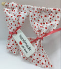 A pair of handmade white fabric curtain panels with a red heart pattern, tied with pink ribbons and a white tag that reads 'Handmade with love'.