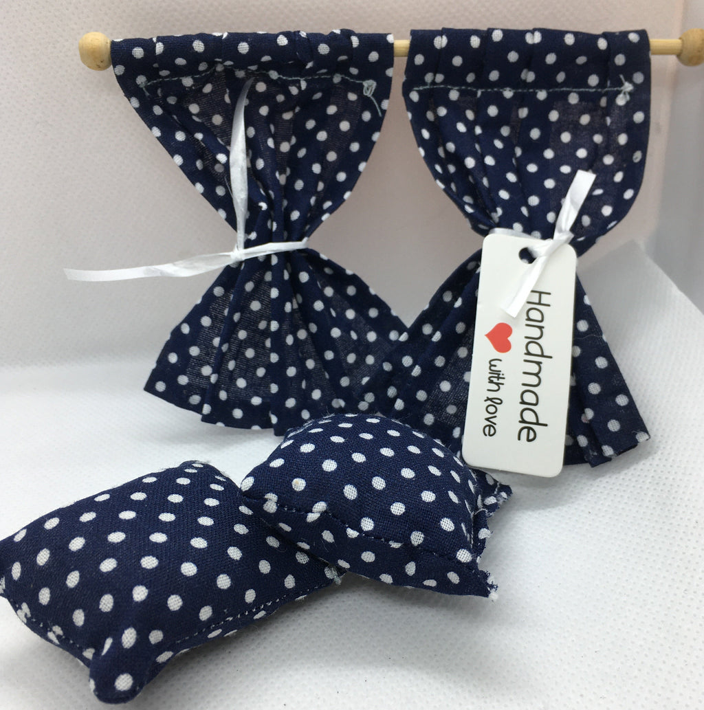 Handmade curtains and cushions, made from navy blue and white polka dot fabric, for any room in your dolls house on a white textured background. A white paper tag on the curtain reads 'Handmade with love'.