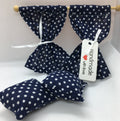 Handmade curtains and cushions, made from navy blue and white polka dot fabric, for any room in your dolls house on a white textured background. A white paper tag on the curtain reads 'Handmade with love'.
