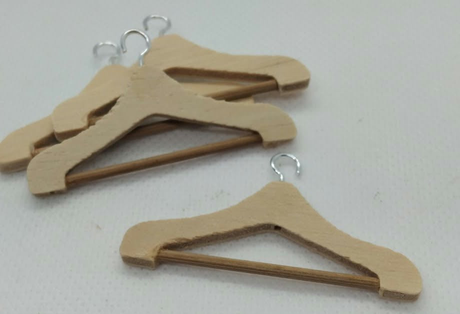 four wooden miniature coat hangers on a white background
