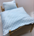A light blue and white gingham check bedding set, including a duvet cover and matching pillowcase, displayed on a miniature wooden bed frame.
