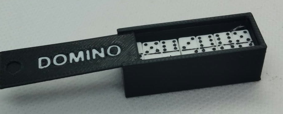 A miniature  black Domino  game container with a sliding lid showing the dominos inside, set against a plain light gray background.