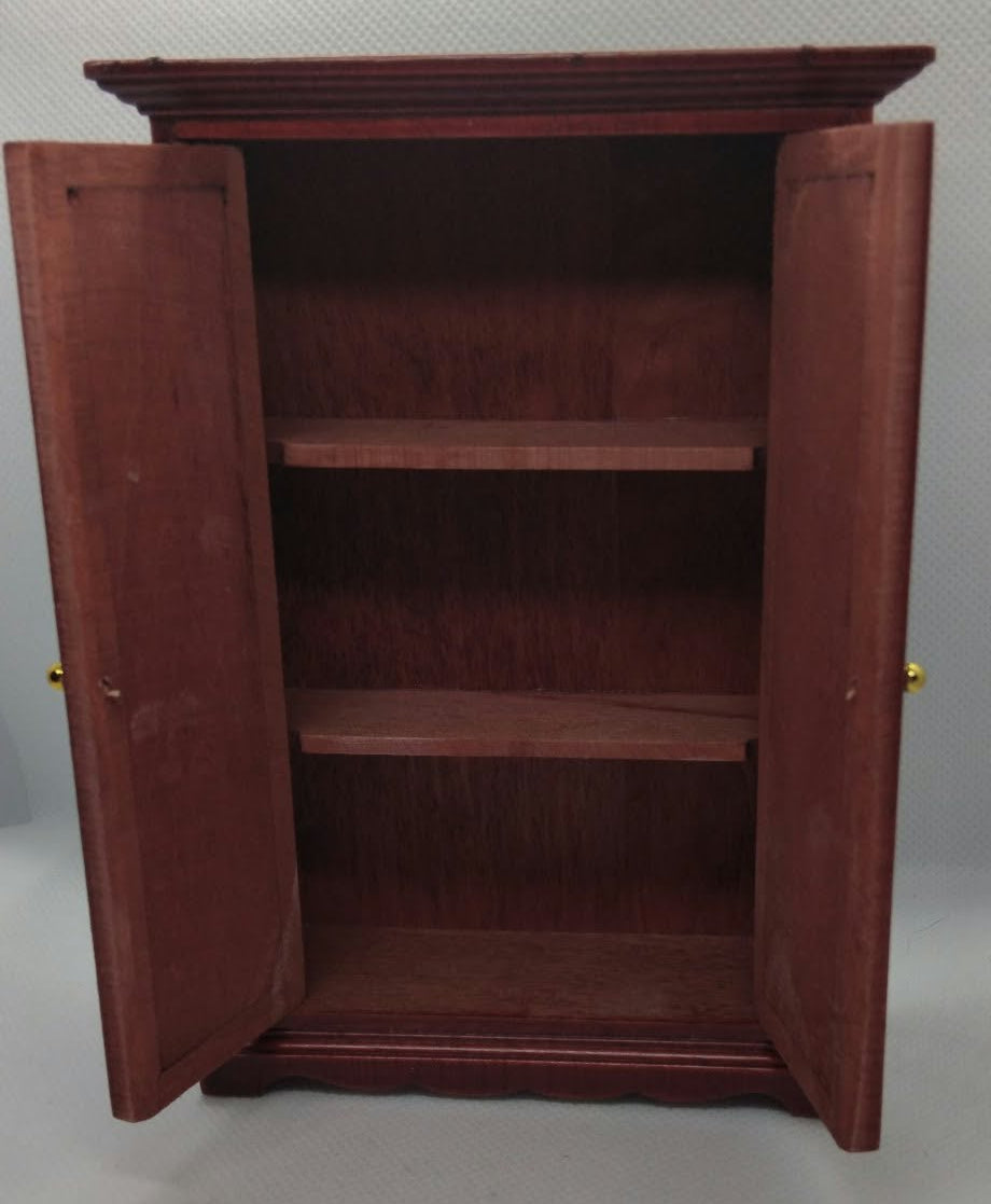 A reddish-brown wooden miniature wardrobe with two doors swung open to show three interior shelves, photographed against a plain light gray wall and floor.