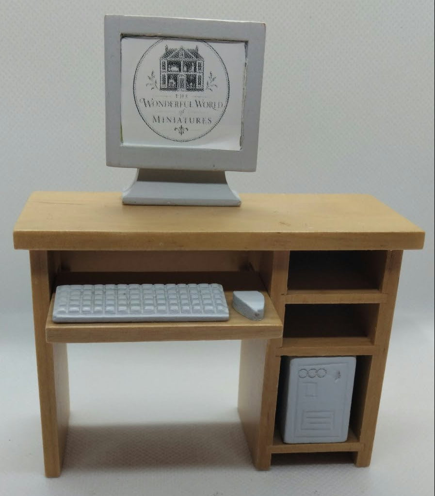 A miniature wooden computer desk with a monitor, keyboard, mouse, and storage compartments, shown on a plain white background.