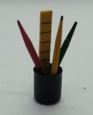 A small black cylindrical holder containing several thin colored pencils, photographed on a plain white surface .