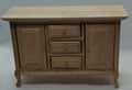 A miniature wooden sideboard cabinet with three drawers and two doors, featuring a light oak wood grain finish and small brass-colored knobs, photographed against a neutral gray background.