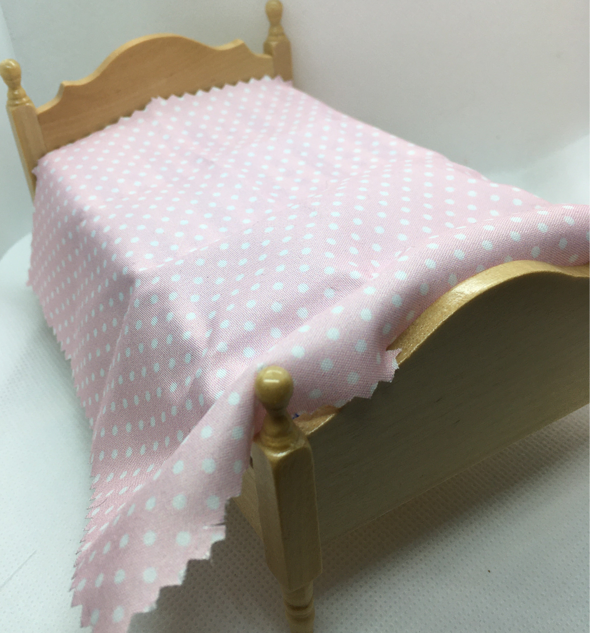 pink polka dot in white, bed sheet on a miniature pine bed with a white background.