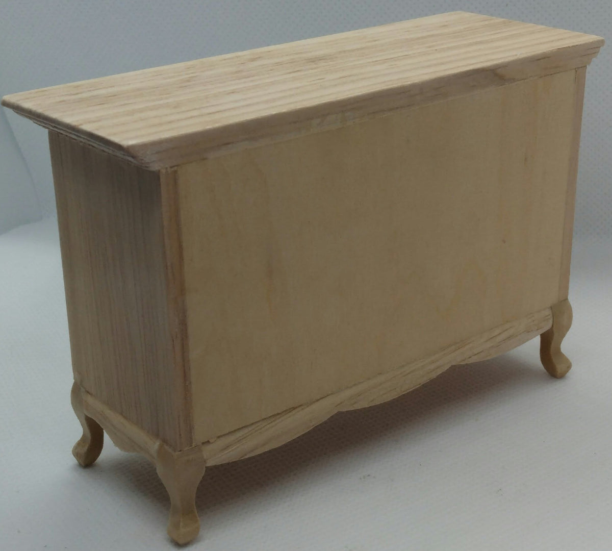 A small unfinished wooden pine cupboard with a light natural wood finish, photographed on a plain light gray studio background.