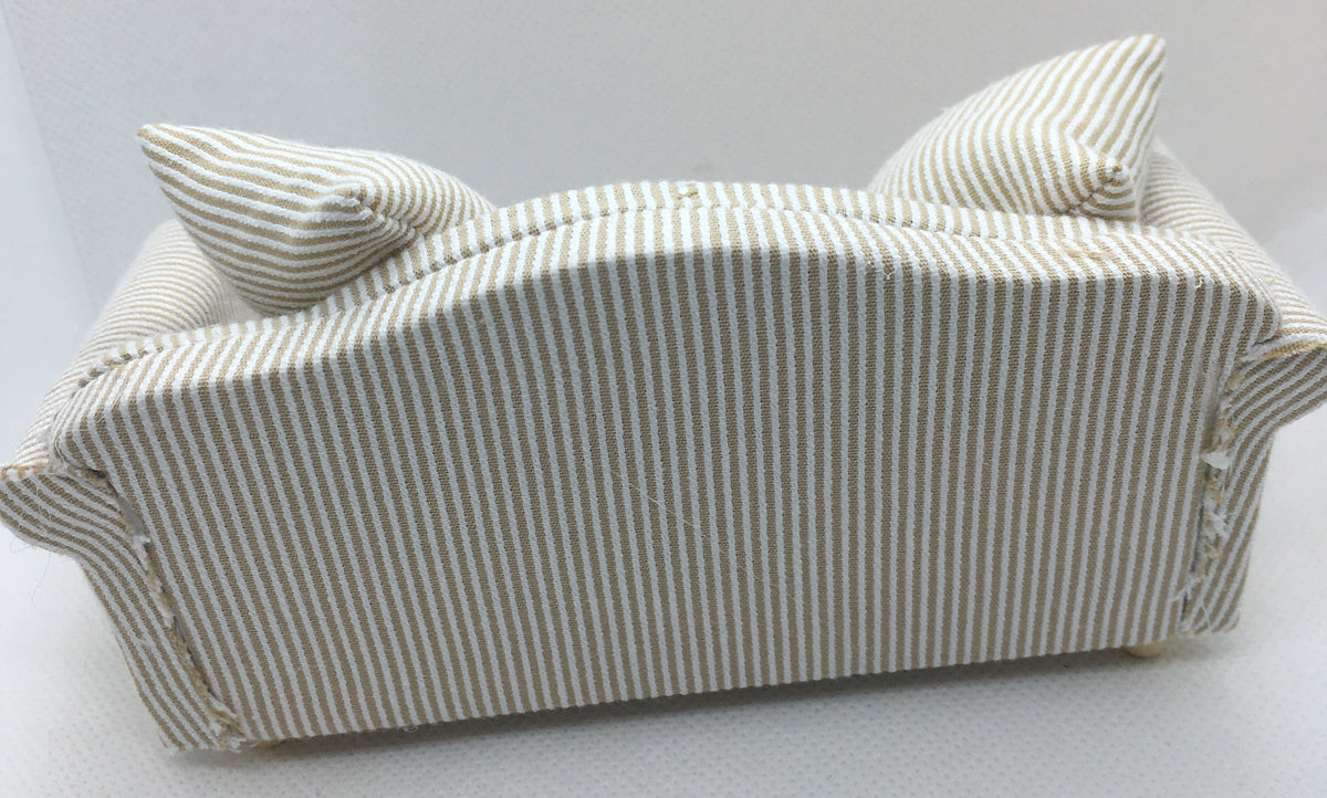 A miniature fabric sofa cover or dollhouse sofa with a beige and white vertical stripe pattern, featuring two matching striped pillows, shown against a plain white background.