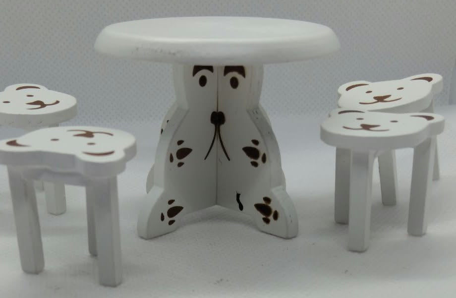A miniature white dollhouse furniture set featuring a small round table and four matching chairs, all decorated with cute teddy bear face details.