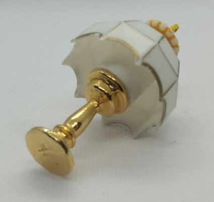 A small gold and white decorative miniature lamp with a cylindrical white body and gold-toned top, photographed on a plain light background.