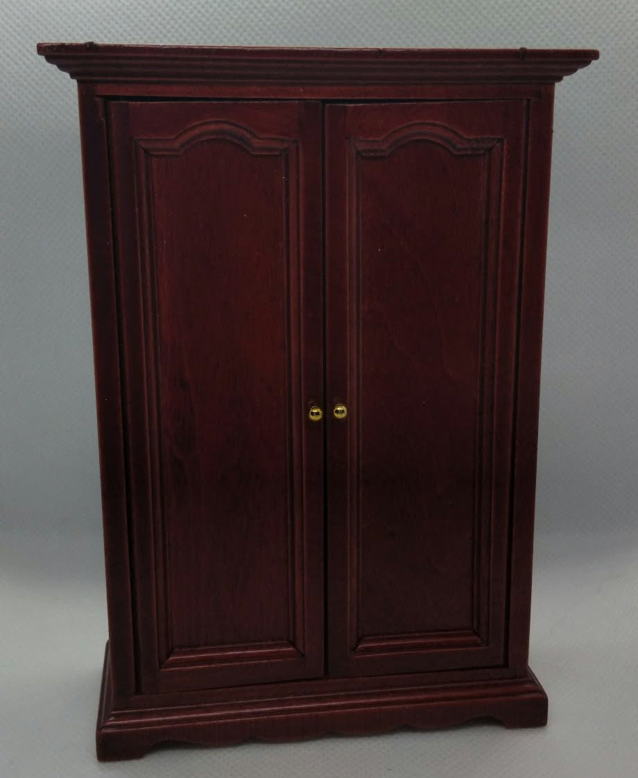 A dark reddish-brown wooden cabinet with two doors and small gold knobs, photographed against a plain light gray backdrop.